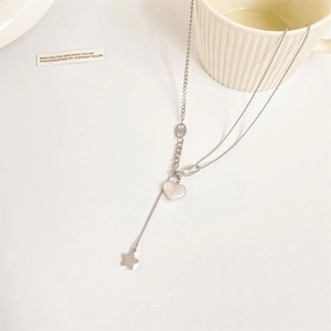 Elegant silver heart necklace with star tassel pendant on cream aesthetic background