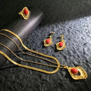 Close-up of vintage gold jewelry set featuring red stone necklaces, ring, and earrings