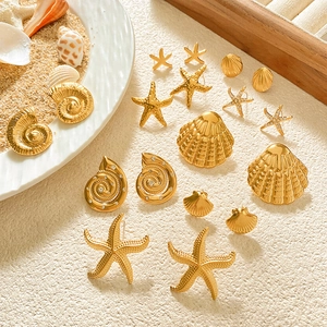 Golden sea shell and starfish stud earring set displayed on a white sandy beach background