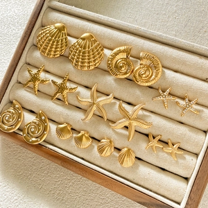 Golden sea shell and starfish stud earring set displayed in a wooden jewelry box