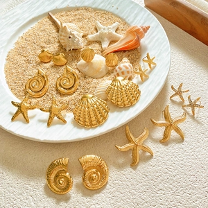 Golden starfish and conch earrings collection on sand beach background for summer