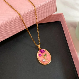 Dettaglio della collana floreale in smalto dorato con pendente rosa e perla su portagioie