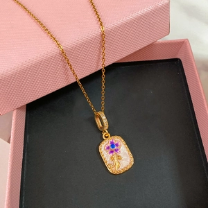 Dettaglio del ciondolo in smalto dorato con motivo floreale viola e zirconi su una collana