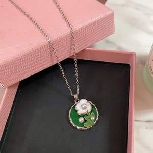 Dettaglio della collana con ciondolo in smalto, fiori 3D bianchi e piccole perle
