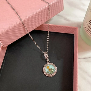 Dettaglio ciondolo fiore in smalto su collana d'argento in confezione regalo rosa