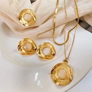 Macro shot of French retro jewelry set with hammered gold texture and moonstone details