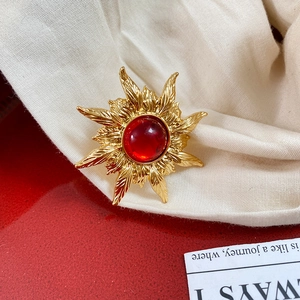Detail of vintage sunburst brooch in gold with a large round red gemstone center