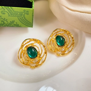Detail view of gold wave earrings with oval green gemstone in a vintage gift box