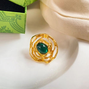 Macro shot of a vintage gold ring featuring a large oval emerald green stone and lava texture