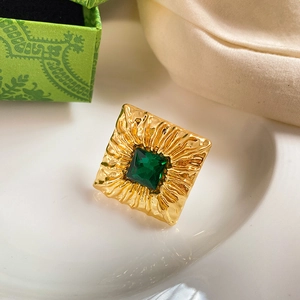 Macro detail of vintage gold square ring with emerald zircon and radiant texture