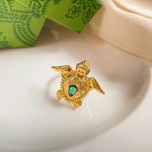 Detailed close-up of golden sea turtle ring with a green teardrop gemstone and white crystals