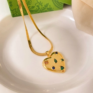Detailed macro view of heart pendant with multi-color zircons on gold flat snake chain