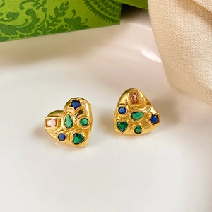 Detail view of heart-shaped gold studs with multi-colored cubic zirconia in vintage style
