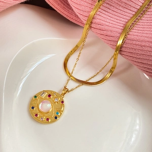 Detailed shot of layered gold necklace with sun moon opal pendant and zircon inlay