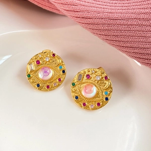 Close-up of golden evil eye stud earrings with colorful zircon inlays on a white tray
