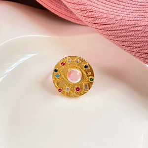 Macro view of gold ring with evil eye design, star moon motifs and pink center stone