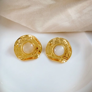 Detail of vintage gold earrings with irregular hammered edges and opal-like stones