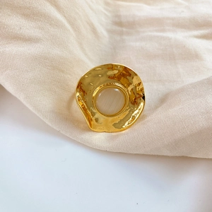 Macro detail of gold-tone hammered texture ring with beige cat-eye stone inlay