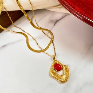 Detail of gold double-layered necklace with irregular pendant and red center stone