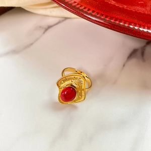 Detailed shot of a vintage gold adjustable ring with an oval red stone on marble