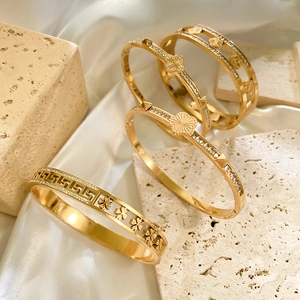 Detail van vier vergulde florale en geometrische armbanden op luxe zijden stof