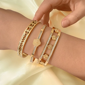 Driedelige set vintage gouden armbanden met bloemen en stras op zijden achtergrond