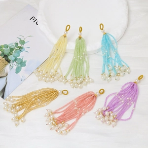 Detalle de borlas de cuentas coloridas con perlas y anillos dorados para joyas DIY