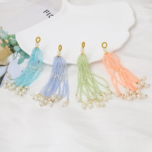 Detalle de colgantes de borlas de cuentas hechos a mano en colores pastel y perlas blancas