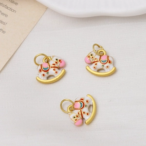 Detailed macro view of three white enamel rocking horse pendants for DIY jewelry making