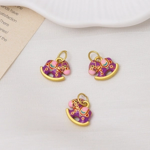 Detailed close-up of three purple enamel rocking horse charms with golden metal alloy bases