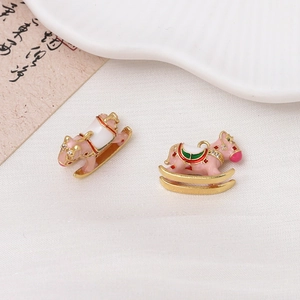 Detailed view of pink enamel rocking horse charm with gold plating and white rhinestones