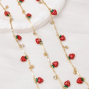 Detail of gold chain necklace featuring red enamel strawberries and sparkling rhinestones