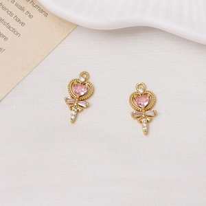 Macro detail of gold-plated fairy wand charms with pink heart zircon and white gemstones