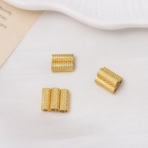 Macro view of gold-plated magnetic cylinder beads with engraved texture for DIY jewelry