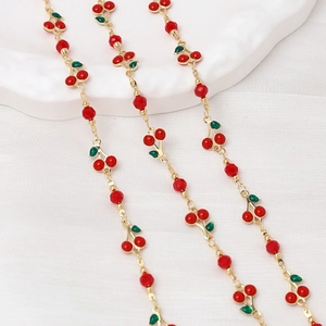Detailed close-up of cherry pendants on a golden chain with red faceted beads