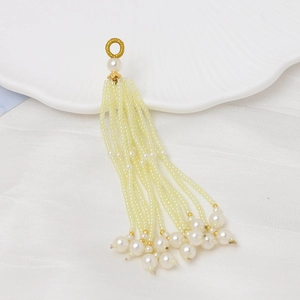 Detalle de borlas de cuentas crema con anillo dorado y grandes perlas redondas