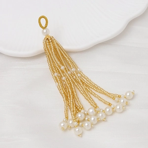 Detalle de borla de cuentas doradas y perlas blancas para creación de joyas DIY