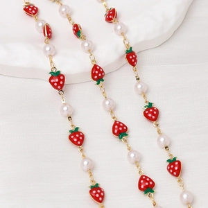 Close-up of sweet red strawberry pendants with white pearls on a golden chain necklace