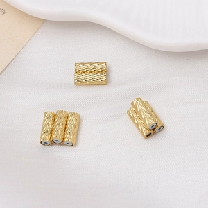 Detailed macro view of gold-plated cylindrical beads with textured diamond-cut surface