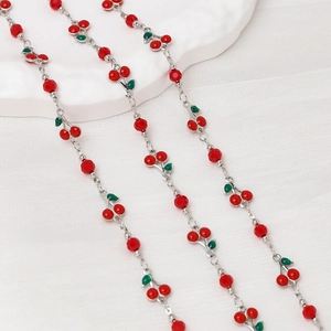 Detail of silver chain with red faceted beads and enamel cherry charms for jewelry
