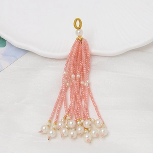 Detalle de borla de cuentas rosas hecha a mano con perla blanca para joyería DIY
