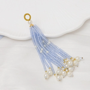 Detalle de borlas de cuentas azul claro con perlas blancas y anillo de metal dorado