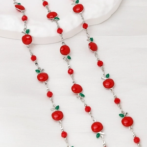 Detail of silver chain necklace with red enamel apple pendants and faceted beads