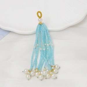 Detalle de borla de cuentas azul claro con perlas blancas de imitación y anillo dorado