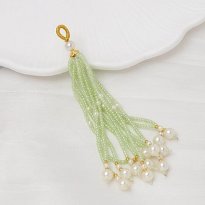 Detalle de borla de cuentas verde claro con perlas blancas para joyería artesanal