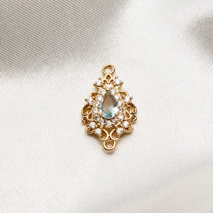 Macro detail of vintage gold teardrop pendant connector with blue zircon and pavé stones