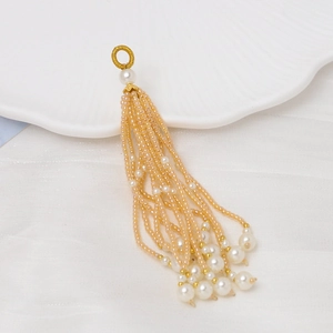 Detalle de borla de cuentas color champán con perlas blancas y un anillo dorado