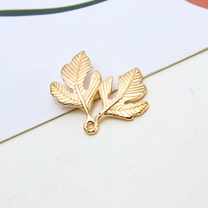 Primer plano de dijes de hojas de ginkgo doradas con texturas detalladas para joyas DIY