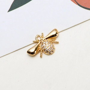 Macro shot of gold-plated bee pendant with white zircon stones for jewelry making