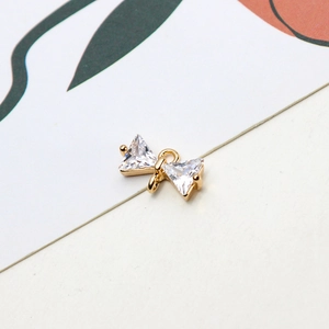 Macro view of bow-shaped gold pendant with cubic zirconia and dual loops for DIY jewelry